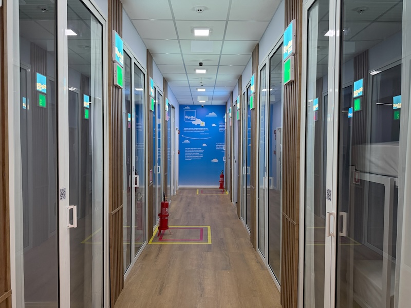 BH Airport inaugura cabines de descanso para os passageiros 10 Nove cabines de descanso, com funcionamento 24h por dia, nos sete dias da semana. Esta é a novidade que o BH Airport está trazendo para os passageiros, em parceria com a Siesta Box, empresa especializada em micro-hotelaria em aeroportos. As cabines têm 5m² e foram projetadas para oferecer conforto, privacidade e praticidade aos viajantes que precisam de algumas horas de descanso em longas conexões, antes ou depois dos voos. Cada unidade é equipada com cama, ar-condicionado e TV a cabo, permitindo períodos de descanso de até 12 horas. Uma das nove cabines também foi projetada para garantir a acessibilidade dos clientes, com um layout diferenciado, que conta com uma cama de casal, substituindo os tradicionais beliches. “Nosso propósito é aprimorar a experiência do passageiro, oferecendo serviços que combinem eficiência, conforto e conveniência. A inauguração das cabines da Siesta Box está alinhada a esse compromisso e reforça nossa vocação para a hospitalidade, com uma solução prática e confortável para proporcionar momentos de descanso ao longo da viagem. Parcerias como essa ampliam o portfólio de serviços do terminal mineiro e contribuem para uma jornada mais completa e qualificada para os passageiros”, ressalta o gerente Comercial do BH Airport, Geovane Medina. Em média, 40 mil passageiros circulam diariamente pelo BH Airport. Em 2025, a movimentação no terminal mineiro superou a marca de 13,3 milhões de passageiros. O volume recorde representa um avanço de 19,2% na comparação com 2019, último ano antes da pandemia, e um crescimento de 7,8% em relação a 2024, quando 12,3 milhões de viajantes embarcaram ou desembarcaram no BH Airport. No acumulado do ano em 2025, o recorte para os passageiros de voos internacionais sinaliza um aumento de 30,3% em comparação com 2019. Em relação aos passageiros de voos domésticos, o incremento foi de 18,8%. De acordo com o sócio-fundador da Siesta Box, Tuca Andrade, a inauguração no BH Airport significa a concretização de um projeto muito esperado pela empresa e pelos clientes. “Belo Horizonte sempre esteve no nosso radar. O BH Airport tem uma alta movimentação, localização estratégica e voos para diversas cidades brasileiras, o que aumenta a concentração de potenciais clientes que precisam de duas ou três horas de descanso, num formato oferecido pela Siesta Box. Por tudo isso, inaugurar essa unidade é motivo de grande satisfação e expectativa”, destaca Andrade. O acesso às cabines será feito de forma avulsa, por reservas realizadas previamente no site da Siesta Box, e por meio dos programas Priority Pass e LoungeKey. Além do BH Airport, a Siesta Box opera nos aeroportos de Campinas e Brasília, consolidando a atuação em terminais estratégicos do país. O investimento reflete a confiança da empresa no potencial do terminal mineiro e na crescente busca por soluções de conforto e bem-estar durante a jornada de viagem.